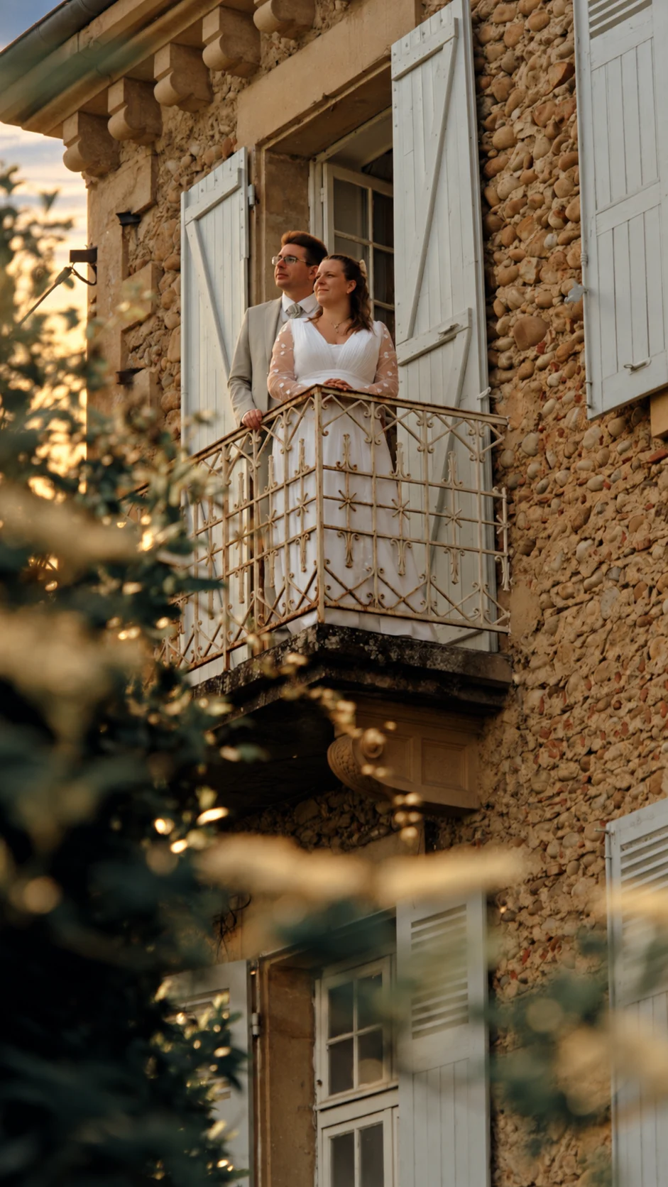 Deux mariés au balcon d’une maison de pierre