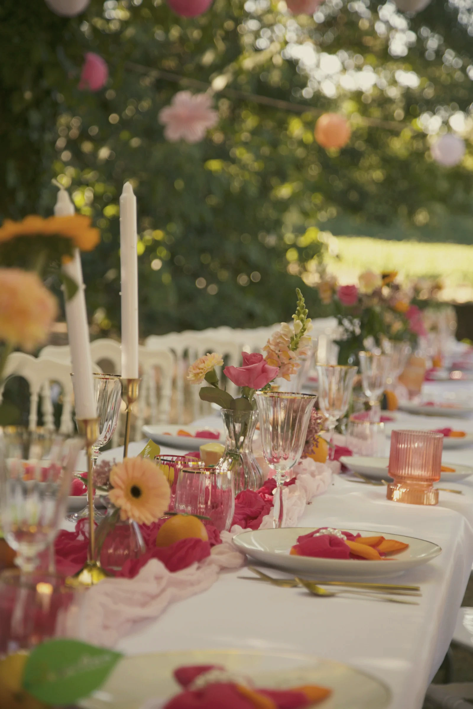 Longue table de mariage fleurie installée sous les arbres